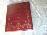 a red book sitting on a bed with a white sheet