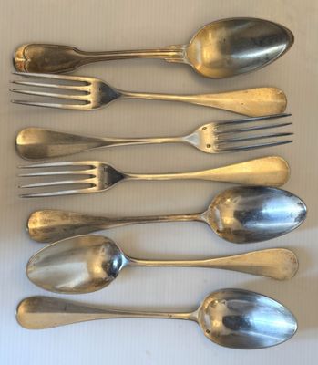 six cuillères et six fourchettes sont alignées sur une table