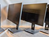 three computer monitors sitting on top of a table next to each other