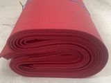 un tapis de yoga rouge enroulé sur un plan de travail blanc