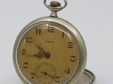 a silver pocket watch sitting on top of a white table