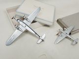 two small model airplanes sitting on a table next to a book