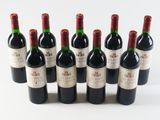 six bottles of red wine lined up in a row on a white surface