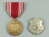 two medals with a red ribbon and a silver medal on a gray surface