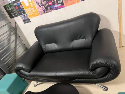 un fauteuil en cuir noir et un repose-pieds dans un coin de la pièce