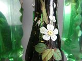 un vase noir sur lequel est peinte une fleur blanche