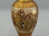 a gold vase with a painting on it sitting on a table