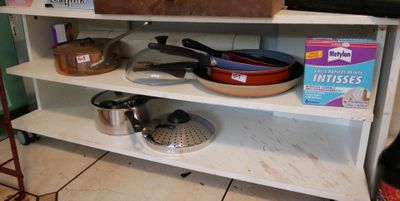 une étagère sur laquelle sont posés des casseroles et des poêles, dans la cuisine