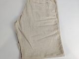 Le short est de couleur beige et comporte une étiquette blanche sur le côté.