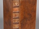 an old book with a brown leather cover sitting on top of a table