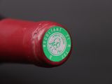 a close up of a red wine bottle with a green label