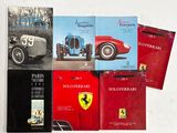 plusieurs livres posés sur une table blanche, avec une voiture rouge et une voiture noire
