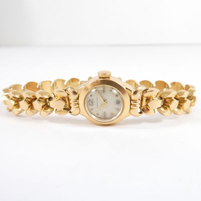 a close up of a gold wrist watch on a white surface