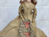 a doll that is dressed in a dress and coat