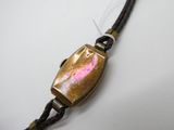 un gros plan d'un bracelet muni d'un fermoir métallique, posé sur une surface blanche