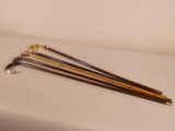 four wooden canes are lined up on a white surface