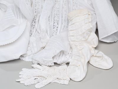 une robe blanche et des gants posés sur une table à côté d'une assiette