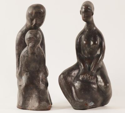 two sculptures of a man and a woman sitting on a chair