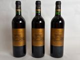 three bottles of wine are lined up on a white surface