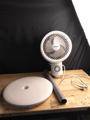 un éventail blanc posé sur une table en bois à côté d'une chaise noire