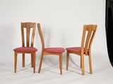 two wooden chairs sitting next to each other on a white surface