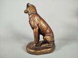 bronze statue of a dog sitting on top of a wooden base