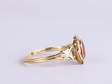 a close up of a gold ring with a red stone in it