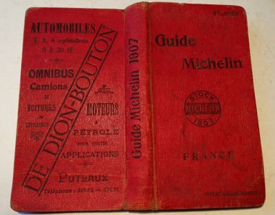an old red book sitting on top of a table next to another book