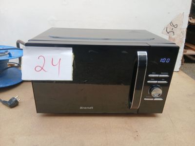 un micro-ondes noir posé sur une table, avec une étiquette de prix accrochée dessus