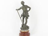 a bronze statue of a man holding a spear on a wooden base