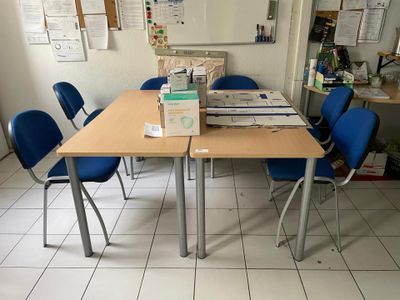 des tables et des chaises dans une pièce où se trouve un tableau blanc accroché au mur