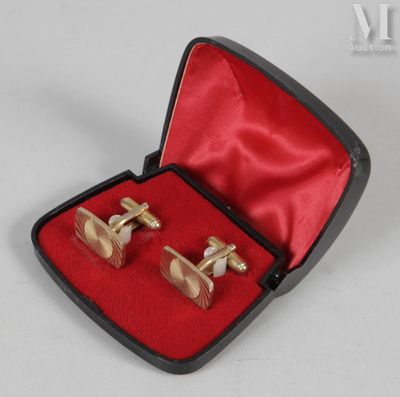 deux paires de boutons de manchette en or dans un étui rouge posé sur un fond blanc
