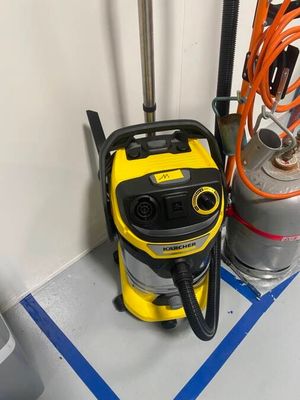 un aspirateur jaune et noir posé par terre à côté d'un bidon d'essence