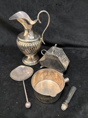 une image représentant un pichet en argent, une cuillère et d'autres objets sur fond noir