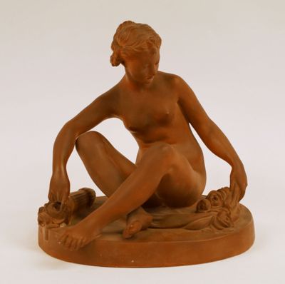 statue d'une femme nue assise sur un socle, les jambes croisées