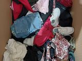 a cardboard box full of clothes and shoes on the floor