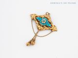 an image of a gold broochle with turquoise stones on it
