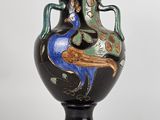 un vase noir orné d'un paon sur fond blanc