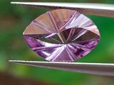 quelqu'un tient une paire de pinces ornées d'un diamant violet