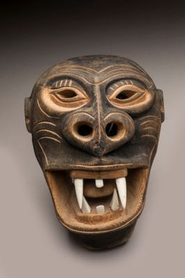une image représentant un masque en bois avec des dents et des crocs