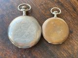 two antique pocket watches sitting on a wooden table