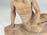 statue of a man sitting on a surfboard on a white surface