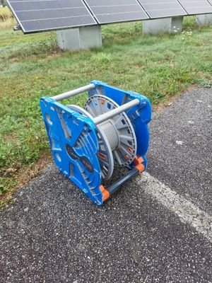 a blue reel sitting on the ground next to a solar panel