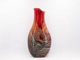 a red and black vase sitting on a white surface