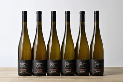 six bottles of white wine lined up on a wooden table