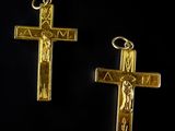 two gold cross pendants on a black background