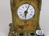 a small gold clock with roman numerals on it