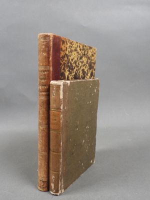 two old books sitting on top of each other on a table