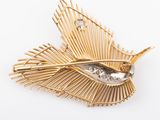 a close up of a gold brooch with a bird on it