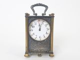 une petite horloge posée sur une surface blanche